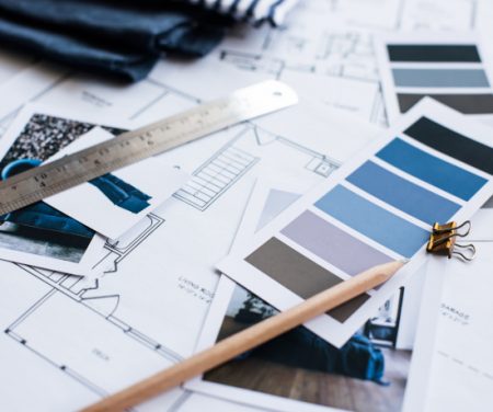 Interior designer's working table, an architectural plan of the house, a color palette, furniture and fabric samples in blue color. Drawings and plans for house decoration.